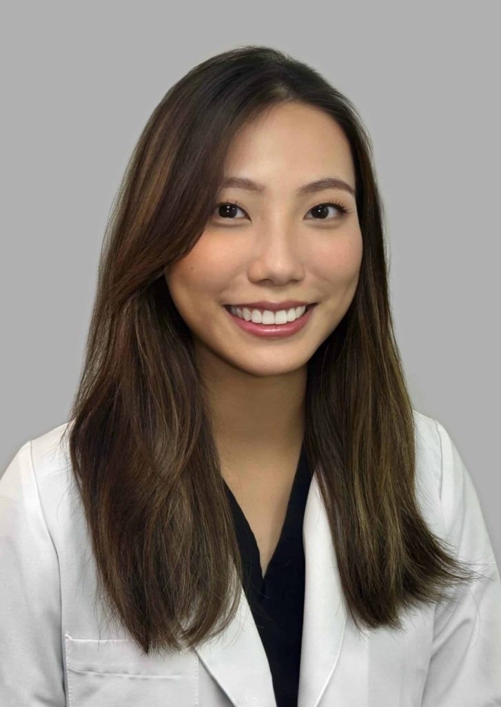 Smiling Asian woman in a white coat, representing a Mandarin speaker improving American English pronunciation.