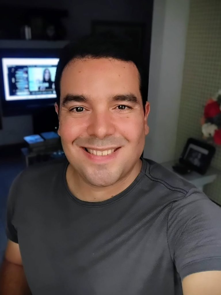 Portuguese speaker smiling confidently after accent modification progress, at home with TV in background.