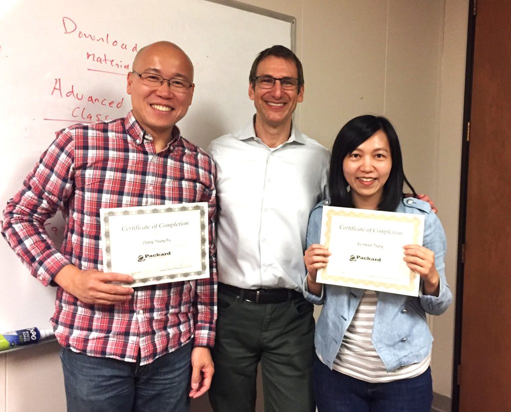 Two students holding certificates after completing an accent modification accent reduction program with their instructor.