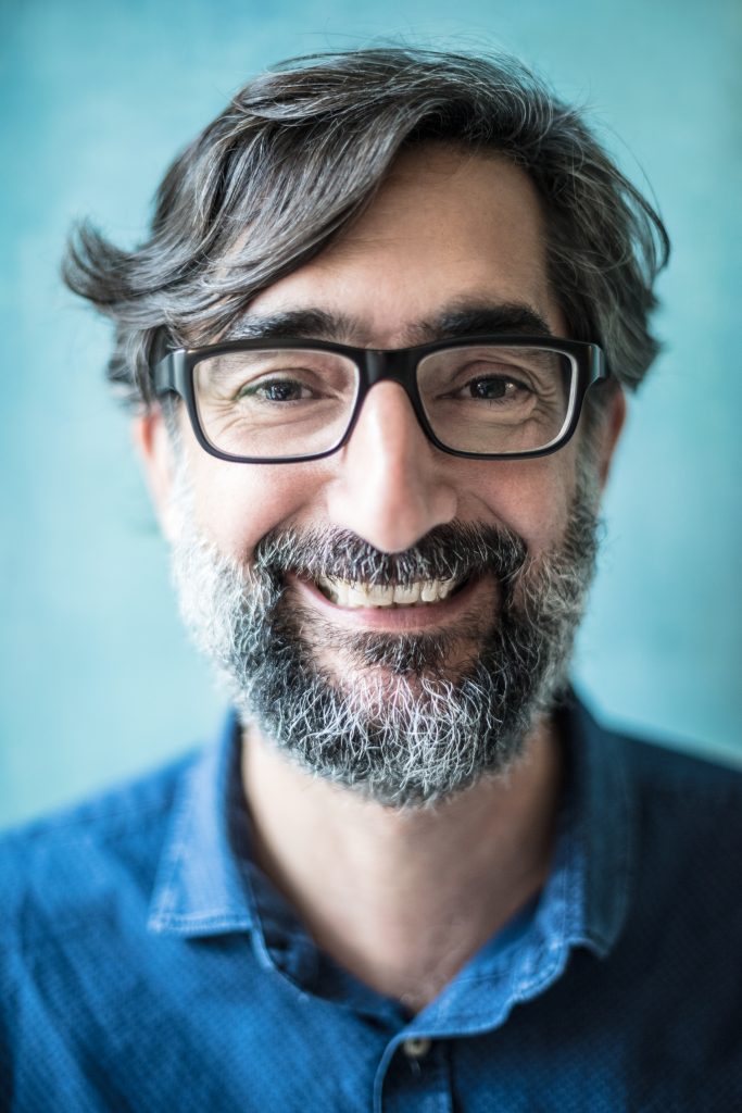 Smiling middle-aged man with glasses and a beard, representing a French speaker improving English pronunciation through French accent modification training.